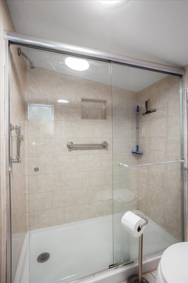 bathroom featuring a shower with shower door and toilet