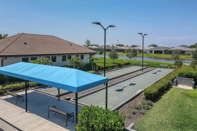 view of property's community with a water view and a lawn