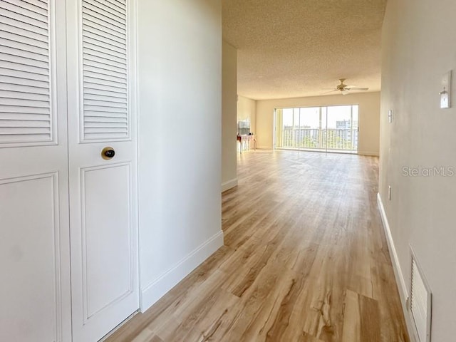 corridor with a textured ceiling and light wood-type flooring