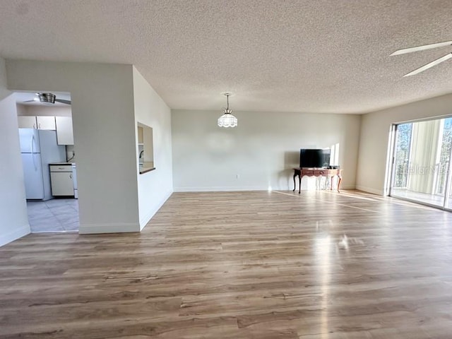 unfurnished living room with ceiling fan, a textured ceiling, and light hardwood / wood-style flooring