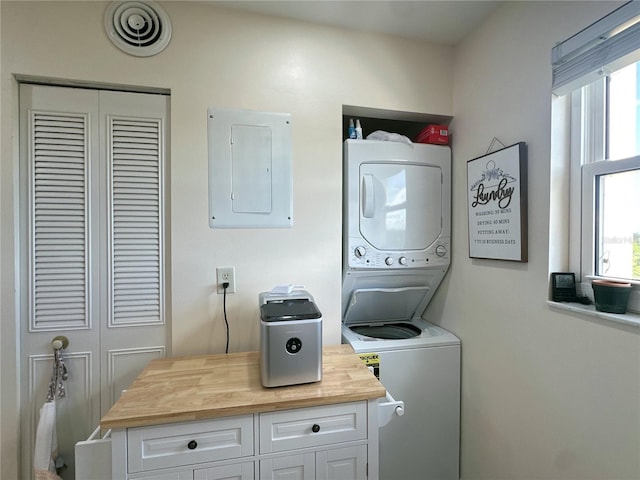 washroom featuring electric panel and stacked washer and clothes dryer