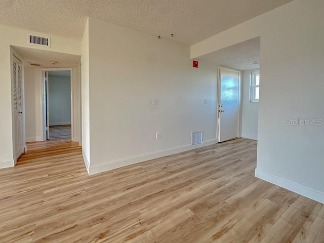 empty room featuring light wood-type flooring and a textured ceiling