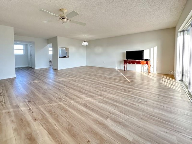 unfurnished living room with ceiling fan, a textured ceiling, and light hardwood / wood-style flooring