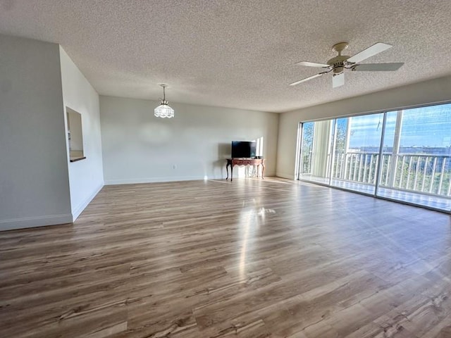 unfurnished living room with hardwood / wood-style flooring, ceiling fan with notable chandelier, and a textured ceiling