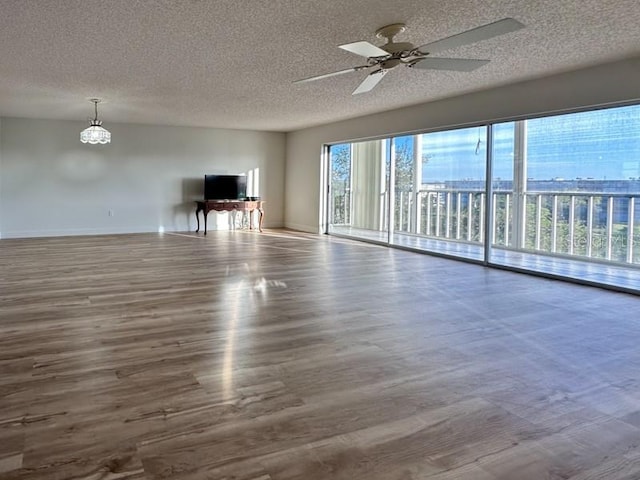 unfurnished living room with ceiling fan with notable chandelier, hardwood / wood-style floors, and a textured ceiling