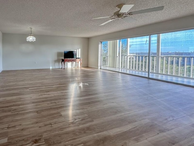 interior space with ceiling fan with notable chandelier, wood-type flooring, and a textured ceiling