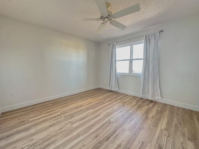 empty room with ceiling fan, light wood-type flooring, and a textured ceiling