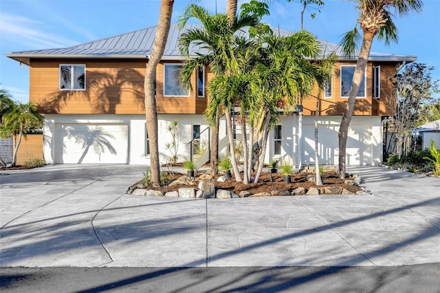 view of front of home with a garage, metal roof, a standing seam roof, and driveway