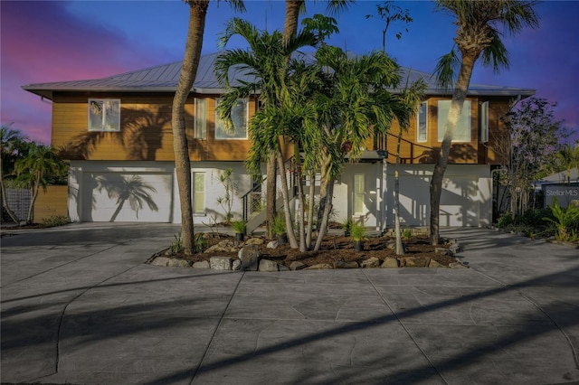 view of front of property featuring a garage, metal roof, and concrete driveway