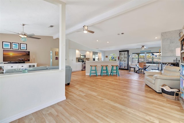 living room featuring vaulted ceiling with beams and light hardwood / wood-style flooring