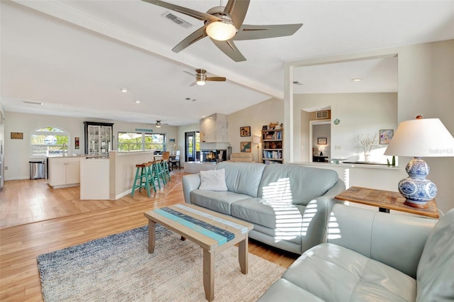 living room with vaulted ceiling with beams and light hardwood / wood-style flooring