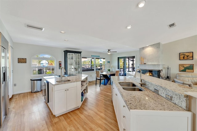 kitchen featuring white cabinetry, a kitchen island with sink, sink, and light hardwood / wood-style floors