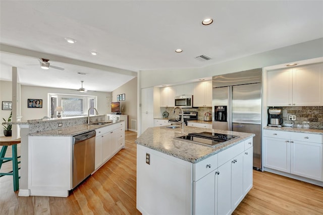 kitchen with stainless steel appliances, white cabinetry, sink, and a spacious island