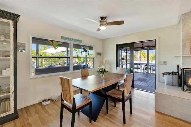 dining room with a fireplace, ceiling fan, plenty of natural light, and light wood-type flooring