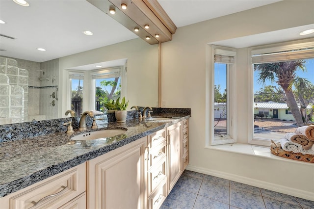 bathroom featuring tile patterned flooring, a tile shower, and vanity