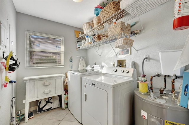 clothes washing area featuring washing machine and dryer, electric water heater, and light tile patterned floors