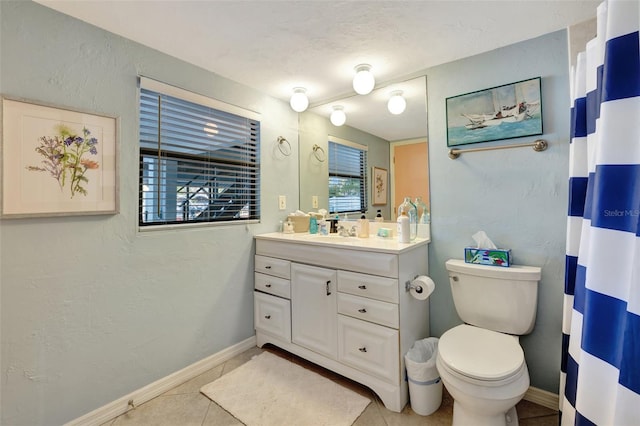 bathroom with tile patterned floors, vanity, toilet, and a wealth of natural light