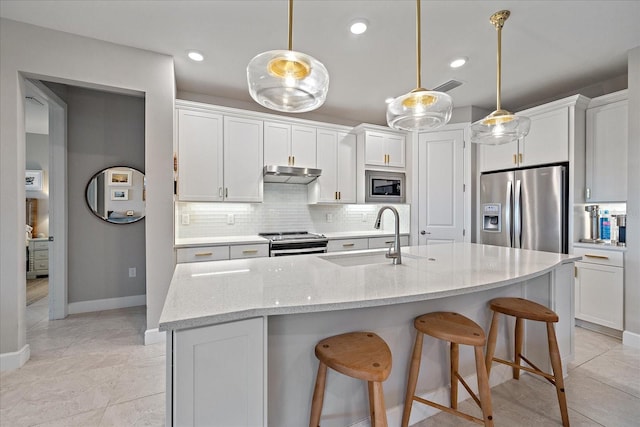 kitchen featuring light stone countertops, pendant lighting, white cabinets, and stainless steel appliances