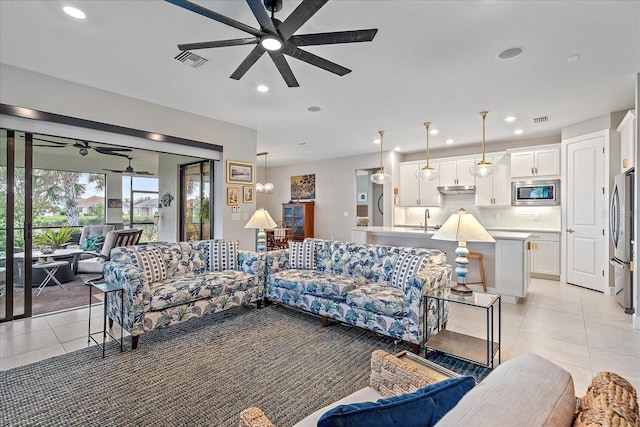 living room with ceiling fan, sink, and light tile patterned floors