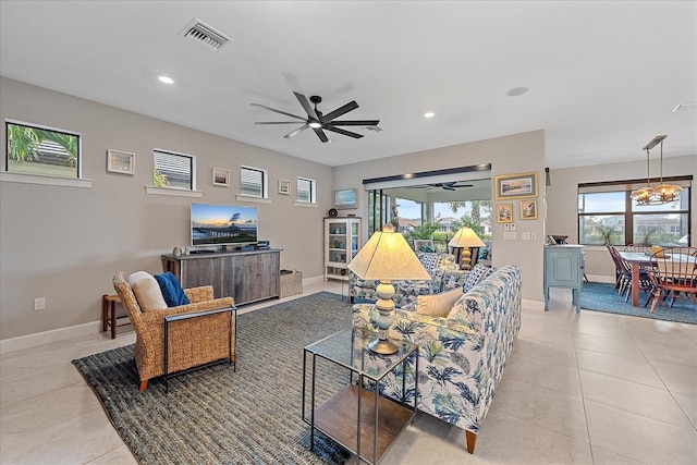 tiled living room featuring ceiling fan with notable chandelier