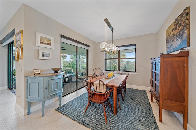 tiled dining space featuring plenty of natural light and an inviting chandelier