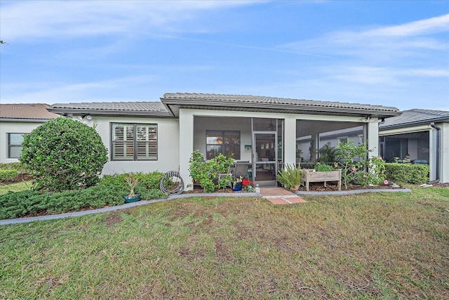 back of house featuring a lawn and a sunroom