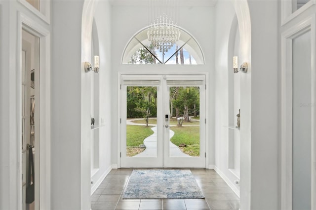 tiled entrance foyer with french doors and a notable chandelier