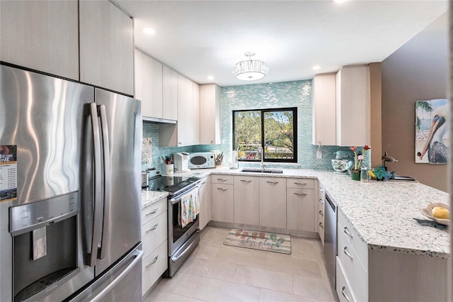 kitchen featuring tasteful backsplash, kitchen peninsula, light stone counters, and stainless steel appliances