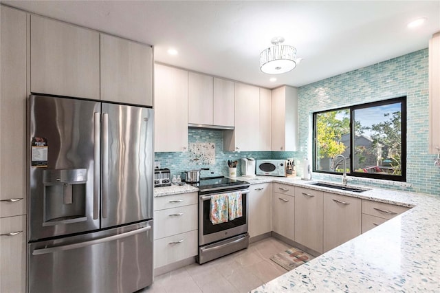 kitchen featuring light stone countertops, appliances with stainless steel finishes, decorative backsplash, sink, and light tile patterned floors