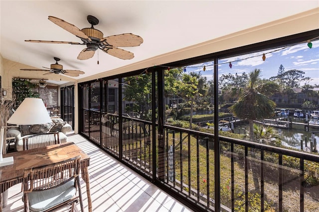 sunroom / solarium featuring ceiling fan and a water view