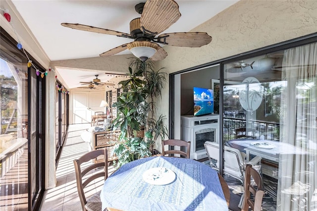 sunroom / solarium with ceiling fan, a fireplace, and vaulted ceiling