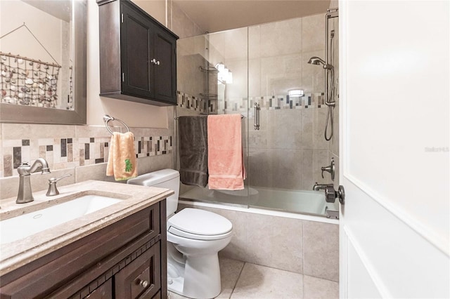 full bathroom featuring toilet, vanity, tile patterned flooring, backsplash, and combined bath / shower with glass door