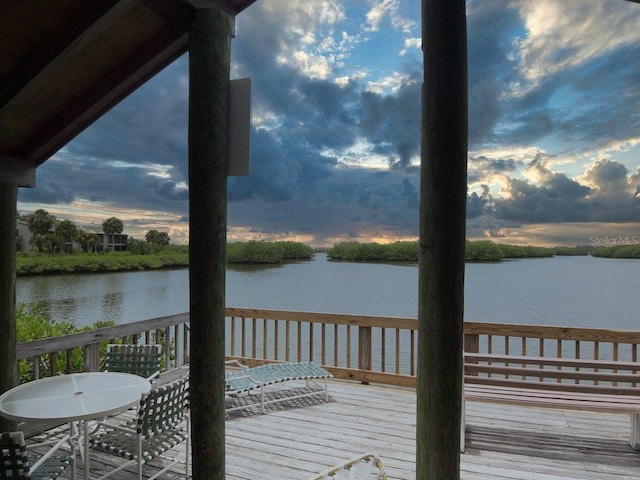 deck at dusk featuring a water view