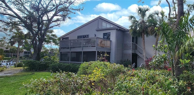 back of house with a balcony, a yard, and a sunroom