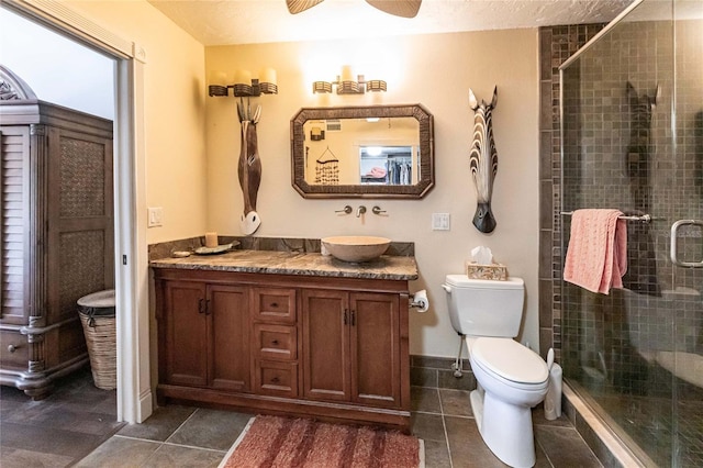 bathroom featuring vanity, a stall shower, tile patterned flooring, toilet, and ceiling fan