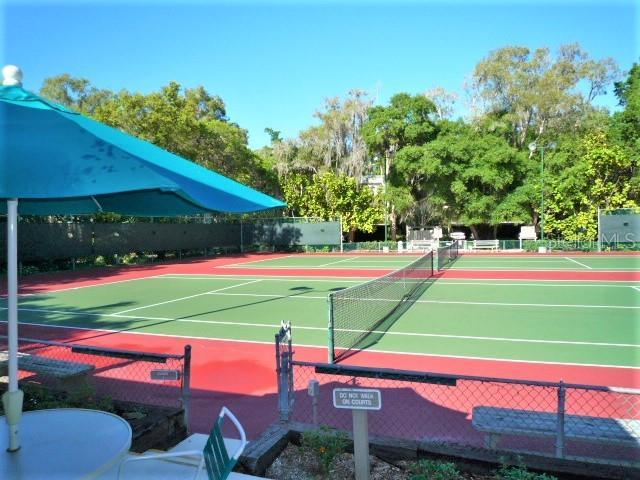 view of tennis court featuring community basketball court and fence
