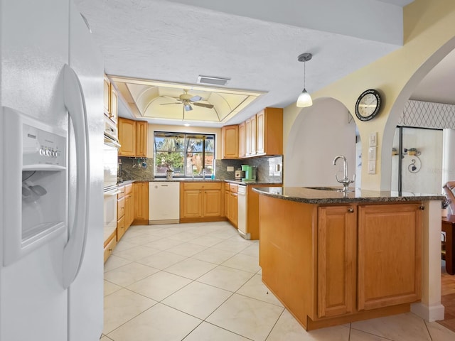 kitchen with pendant lighting, white appliances, a raised ceiling, sink, and kitchen peninsula