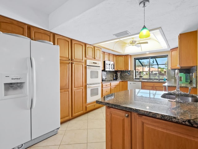 kitchen with sink, dark stone countertops, decorative light fixtures, white appliances, and light tile patterned flooring