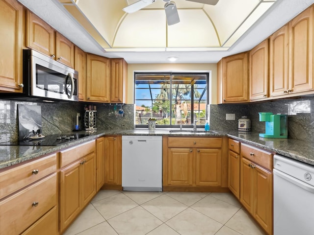 kitchen featuring dishwasher, dark stone countertops, light tile patterned floors, and sink