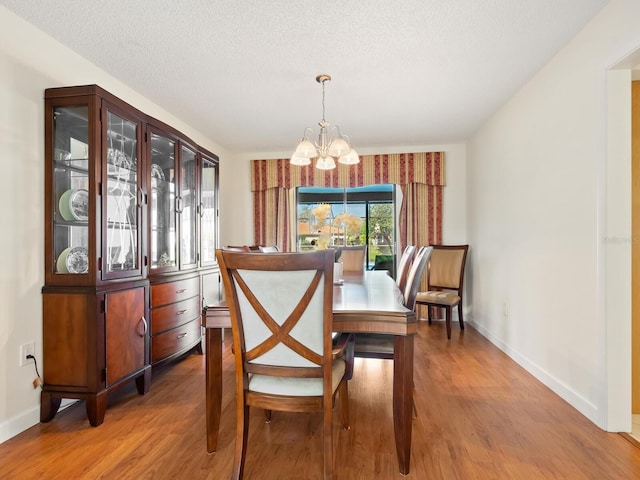 dining area with a notable chandelier, wood-type flooring, and a textured ceiling