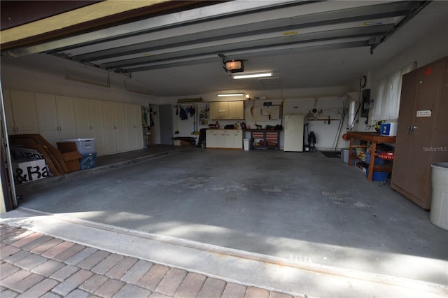 garage with a workshop area, a garage door opener, and white refrigerator