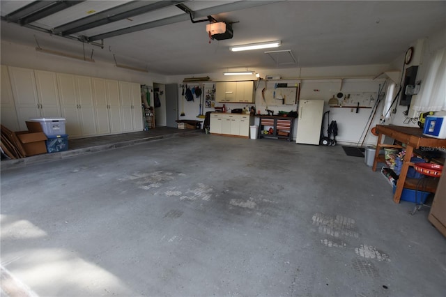 garage featuring a workshop area, white fridge, and a garage door opener