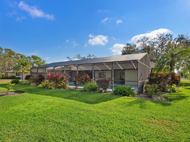 rear view of house with a lanai and a yard