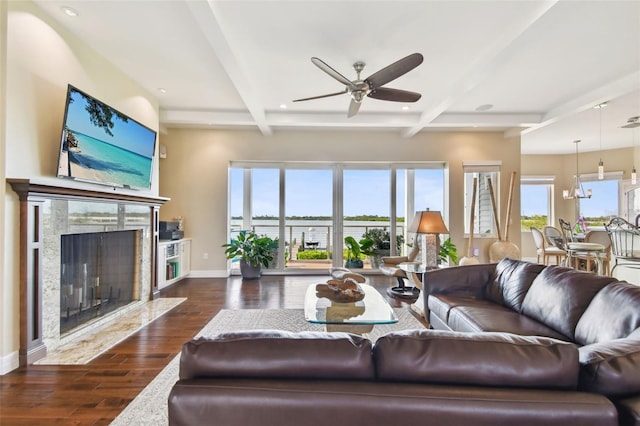 living room featuring beamed ceiling, ceiling fan with notable chandelier, dark hardwood / wood-style flooring, and a fireplace