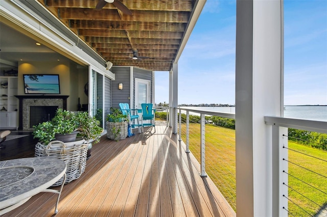 wooden deck featuring a yard, a water view, and ceiling fan