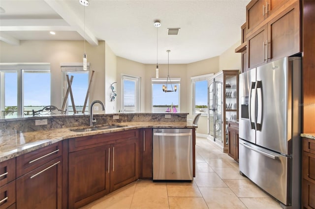 kitchen featuring pendant lighting, sink, light stone countertops, and stainless steel appliances