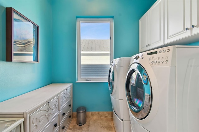 clothes washing area with separate washer and dryer and cabinets