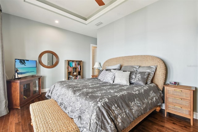 bedroom with a tray ceiling, ceiling fan, and dark hardwood / wood-style flooring