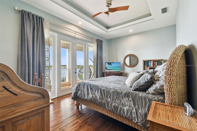 bedroom with hardwood / wood-style floors, ceiling fan, a raised ceiling, and access to outside