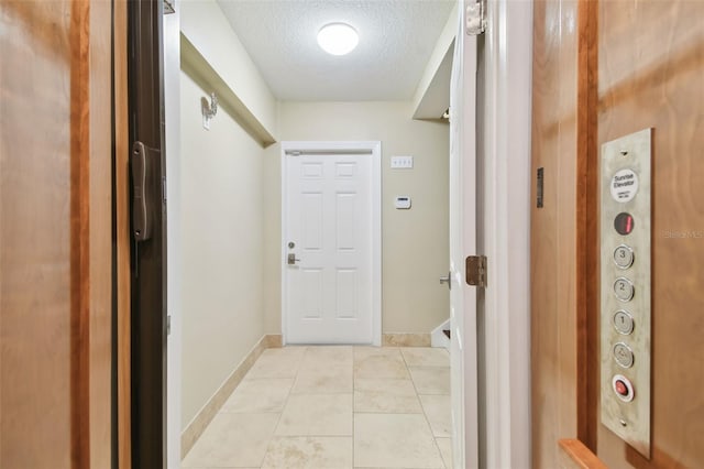 hallway featuring light tile patterned flooring and a textured ceiling